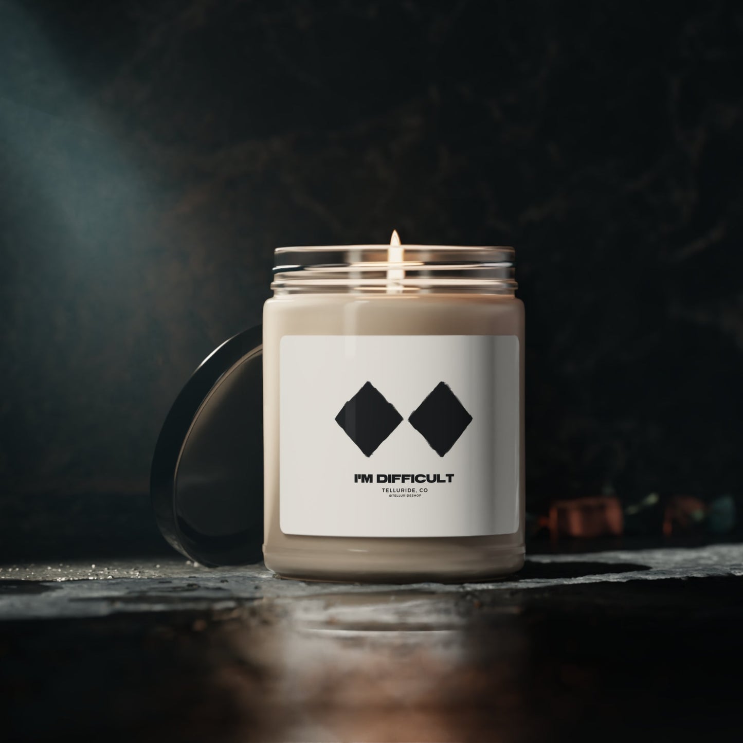 Soy candle with a white label and black lettering saying "I'm Difficult" and two double diamond ski signs. The candle is made of natural soy wax and is perfect for adding a touch of ambiance to any room. The two double diamond ski signs are a reference to the most challenging ski runs at Telluride Ski Resort, making this candle a great way to show your support for the resort and the ski and snowboard lifestyle.
