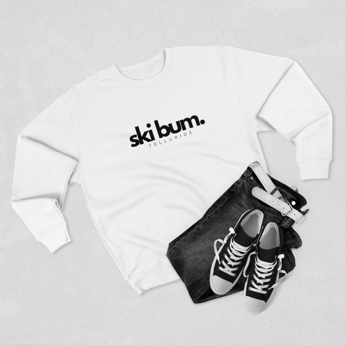 Premium white crewneck unisex sweatshirt with black lettering saying "Ski Bum" and Telluride. The sweatshirt is made of soft, comfortable cotton and is perfect for a day of skiing or snowboarding. The phrase "Ski Bum" is a popular term for someone who loves to ski or snowboard and who lives or spends a lot of time in a ski resort town. This sweatshirt is a great way to show your love of skiing and snowboarding, and your love of the Telluride Ski Resort.