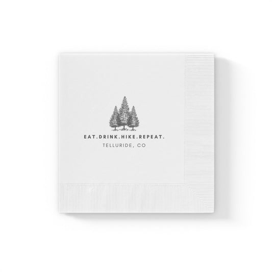 White cocktail napkins with black writing saying "Eat. Drink. Hike. Repeat.". The napkins are made of soft, absorbent paper and are perfect for use at parties, events, or just for everyday use. Celebrate your time at the Telluride Ski Resort, in the mountains and at your next wedding! 