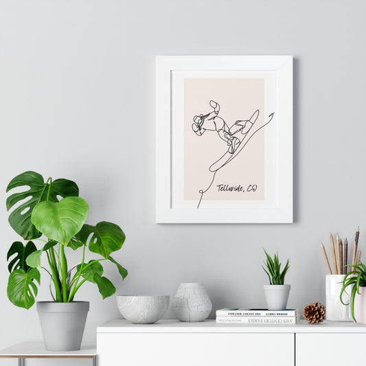 Framed snowboarder drawing on a pink background with the words "Telluride, CO" in black. The drawing is a stylized depiction of a snowboarder flying down the slope. The background is a pink color that contrasts with the black text. The frame is white and simple. The drawing is a unique and eye-catching way to show your love of snowboarding and the Telluride Ski Resort.