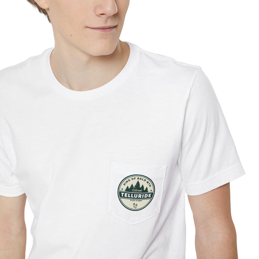 White pocket t-shirt with a circle design featuring lettering saying "King of Bald Mtn.", Telluride, CO. and Elevation 11,880'. The t-shirt is made of 100% cotton and is perfect for a day of skiing or snowboarding at Telluride Ski Resort. Bald Mountain is one of the more famous peaks in Telluride Ski Resort, making this t-shirt a great way to show your support for the resort and the apres ski lifestyle.