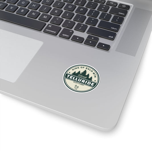 Sticker with a circle design featuring black lettering saying "King of Bald Mtn.", Telluride, CO. and Elevation 11,880'. The sticker is made of durable vinyl and is perfect for sticking to laptops, water bottles, or other belongings. The phrase "King of Bald Mtn." is a popular saying among skiers and snowboarders who have summited Bald Mountain, a mountain in Telluride, Colorado.  This sticker a great way to show your support for the resort and the apres ski lifestyle.