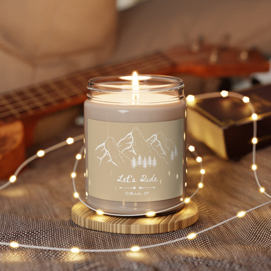 Scented soy candle with a beige label featuring a white outline of the San Juan Mountain Range and white lettering saying "Let's Ride" and Telluride, CO. The candle is made of natural soy wax and is scented with a blend of essential oils that evoke the feeling of being on the slopes. The San Juan Mountain Range is a popular ski destination in Colorado, and the Telluride Ski Resort is one of the most popular resorts in the range. This candle is a great way to bring the feeling of the slopes home with you.