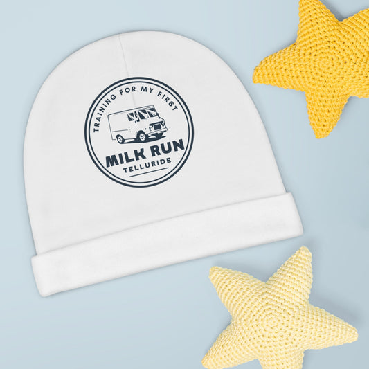 White baby beanie with navy circle print featuring a milk truck and black lettering saying "Training for my first Milk Run" and Telluride. The beanie is perfect for keeping your future skier or snowboarders head warm. The phrase is an ode to Milk Run at the Telluride Ski Resort. 
