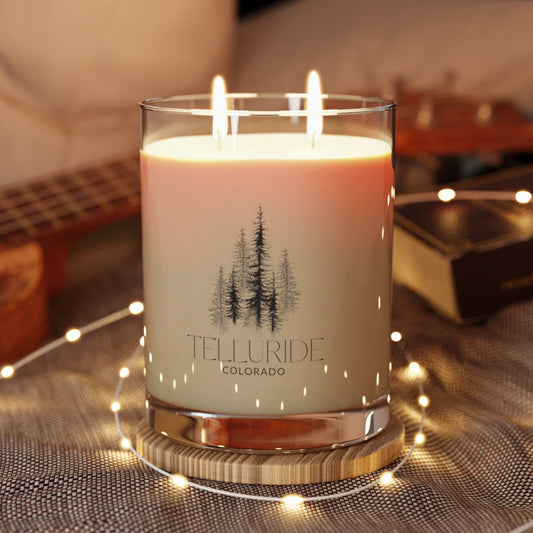 White wax scented glass candle with two wicks and the words "Telluride" and "Colorado" and a picture of trees in black printed on the glass. The candle is a stylish and aromatic way to bring the beauty of Telluride, Colorado and your amazing time at the Telluride Ski Resort into your home. The candle is a great way to relax and unwind after a long day of skiing, snowboardings, shopping or hiking.