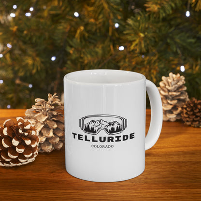 White ceramic coffee mug with black lettering saying "Telluride" and "Colorado". The mug also has a black image of mountains printed inside of ski or snowboard goggles. The mug is a stylish and practical way to enjoy a hot beverage while celebrating your love of Telluride and Colorado. The mug is a great way to show your love of the Telluride Ski Resort and Colorado, whether you're enjoying a cup of coffee at home or taking it with you on your next trip.