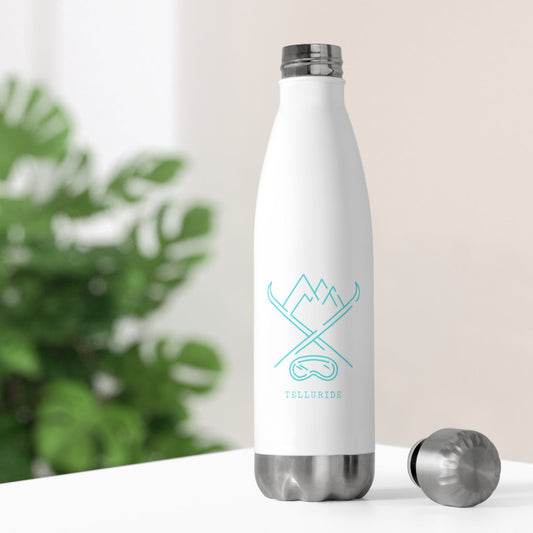 White stainless steel insulated 20oz bottle with a teal image of crossed skis, mountains, and ski goggles. The word "Telluride" is printed in teal on the front of the bottle. The bottle is a stylish and functional way to stay hydrated and show your love of skiing and Telluride. The white bottle is simple and elegant, while the teal image and lettering add a touch of color. The bottle is a great way to enjoy a cold drink on a hot day or to take with you on your next ski trip to the Telluride Ski Resort.