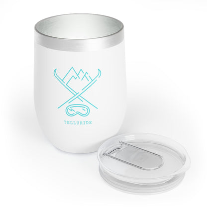 White stainless steel insulated 12oz tumbler with teal lettering saying "Telluride" and an image of crossed skis, mountains, and ski goggles. The tumbler is a stylish and practical way to keep your drinks cold or hot while celebrating your love of skiing at the Telluride Ski Resort.  The tumbler is a great way to show your love of Telluride and Colorado, whether you're skiing, snowboarding, shopping or just relaxing at home.