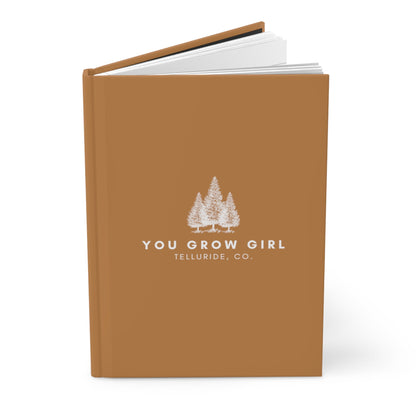 Brown hardcover journal with white lettering saying "You Grow Girl" and "Telluride, CO." The journal is perfect for recording your thoughts, dreams, and adventures. The text is a motivational message to women everywhere to keep growing and learning. The words "Telluride, CO." represent the beauty of the Telluride Ski Resort and the inspiration it can bring.