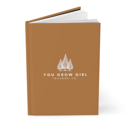 Brown hardcover journal with white lettering saying "You Grow Girl" and "Telluride, CO." The journal is perfect for recording your thoughts, dreams, and adventures. The text is a motivational message to women everywhere to keep growing and learning. The words "Telluride, CO." represent the beauty of the Telluride Ski Resort and the inspiration it can bring.